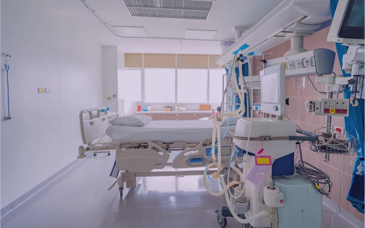 Empty hospital room with patient bed and clinical monitoring equipment.