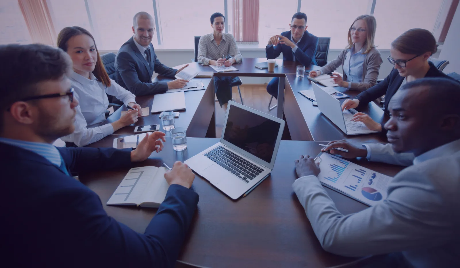 Operations leaders gathered around a boardroom table reviewing delivery data.